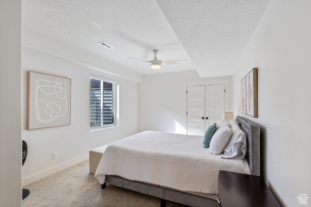 Carpeted bedroom with a textured ceiling, baseboards, and ceiling fan