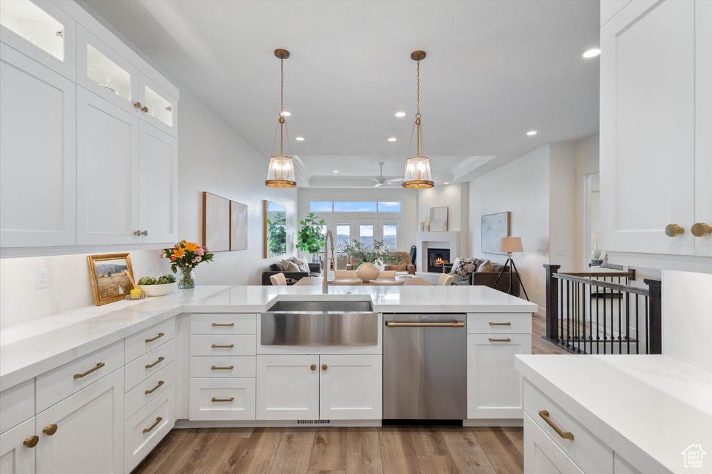 Kitchen featuring a sink, dishwasher, light wood finished floors, white cabinetry, and glass insert cabinets