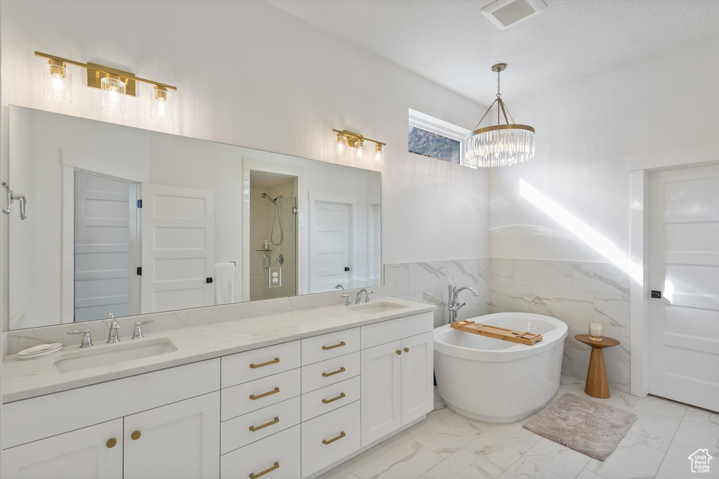 Full bath featuring a chandelier, marble finish floors, a shower stall, double vanity, and wainscoting