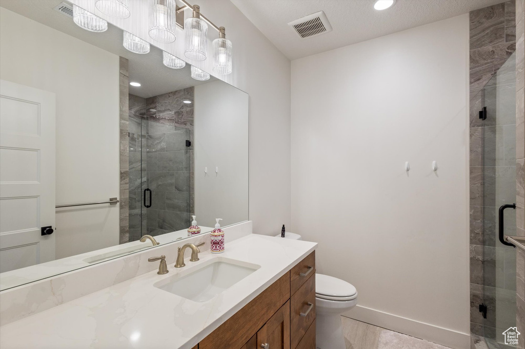 Bathroom featuring a shower stall, toilet, vanity, and baseboards
