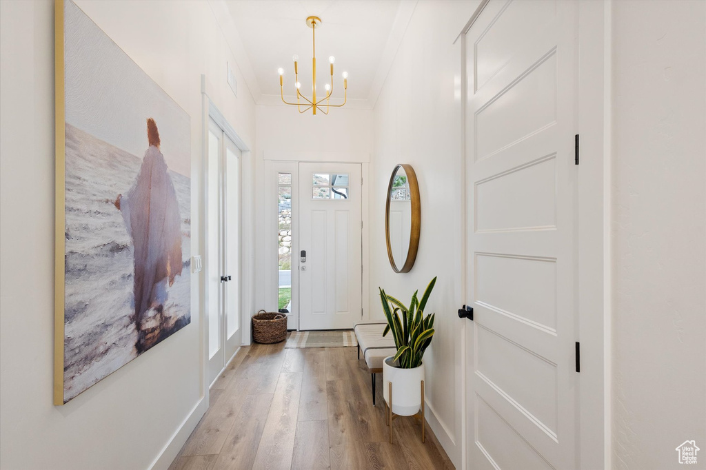 Foyer entrance with a chandelier, light wood-style floors, and baseboards