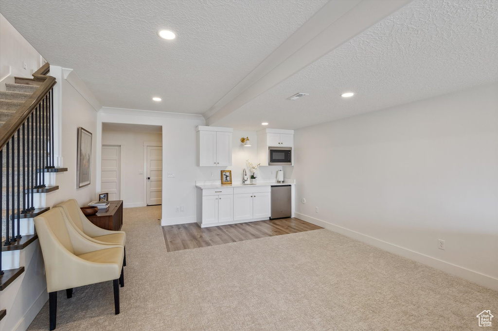 Sitting room featuring light colored carpet, a textured ceiling, baseboards, stairs, and recessed lighting