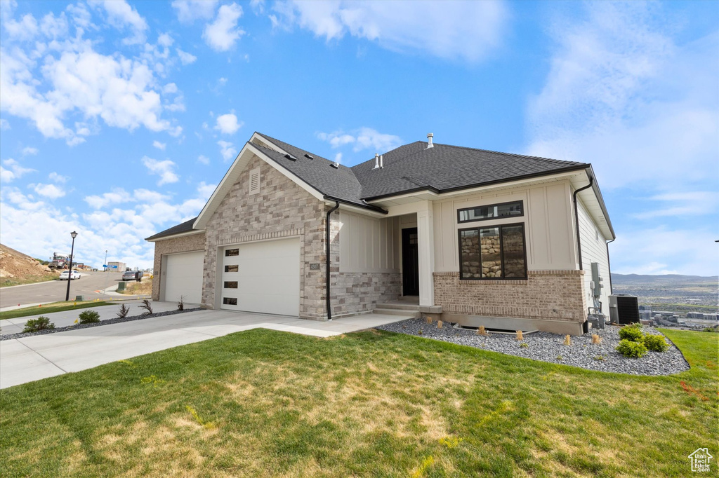 View of front of home with a garage, a front yard, concrete driveway, and brick siding