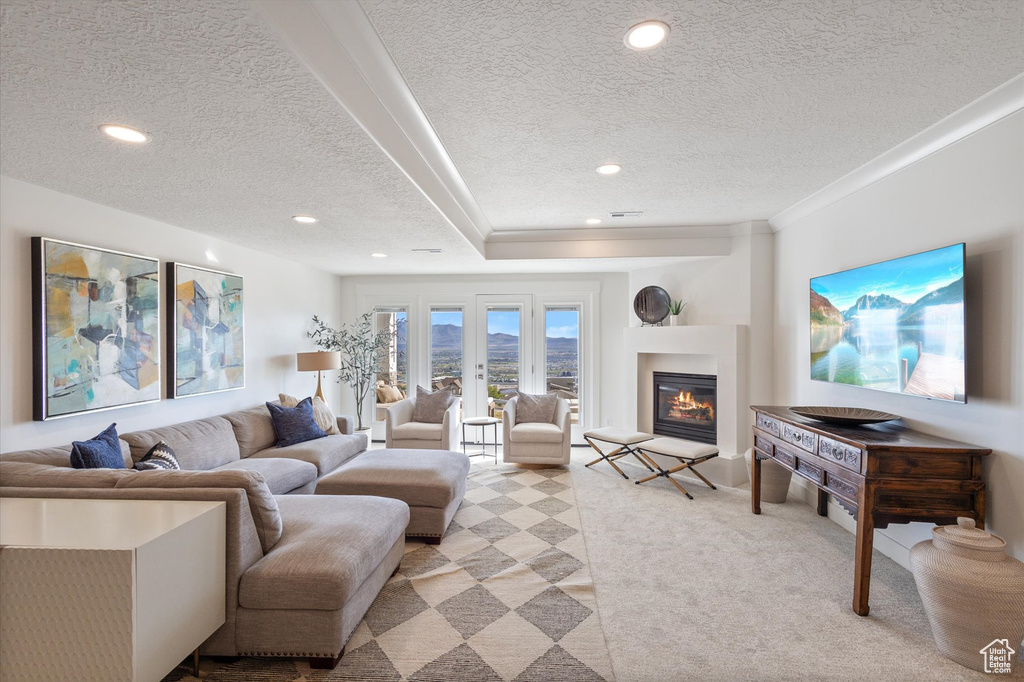 Living room with a textured ceiling, light colored carpet, recessed lighting, a glass covered fireplace, and crown molding