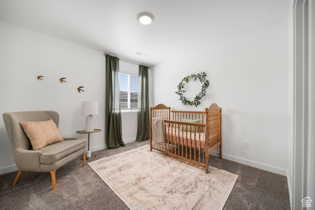 Carpeted bedroom with baseboards and a nursery area