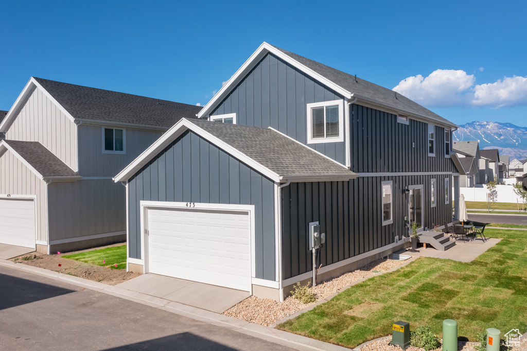 View of front of property with a residential view, a shingled roof, an attached garage, board and batten siding, and a mountain view