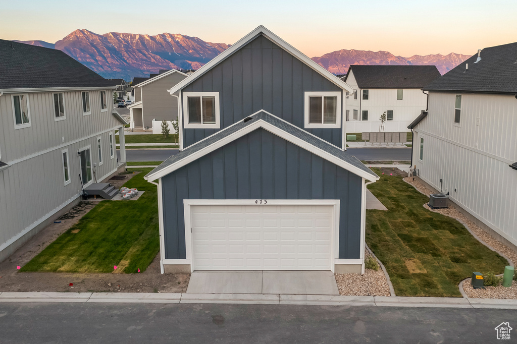 View of front of house featuring a lawn, board and batten siding, a mountain view, and concrete driveway