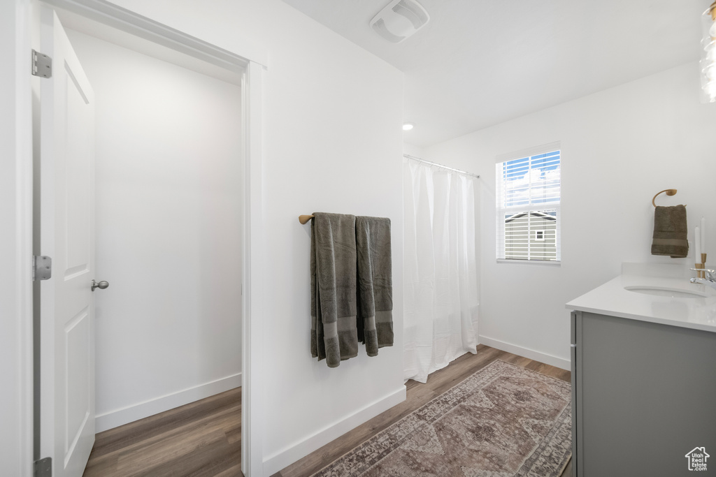 Bathroom with vanity, visible vents, wood finished floors, baseboards, and a shower with shower curtain