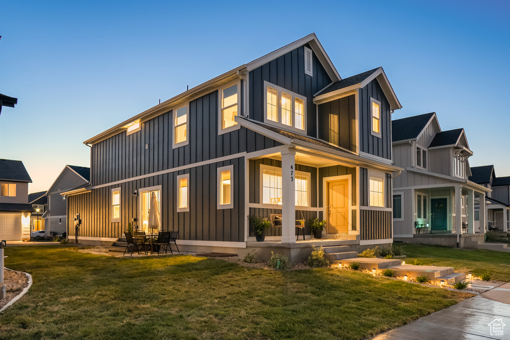 Back of property with a lawn, board and batten siding, and covered porch