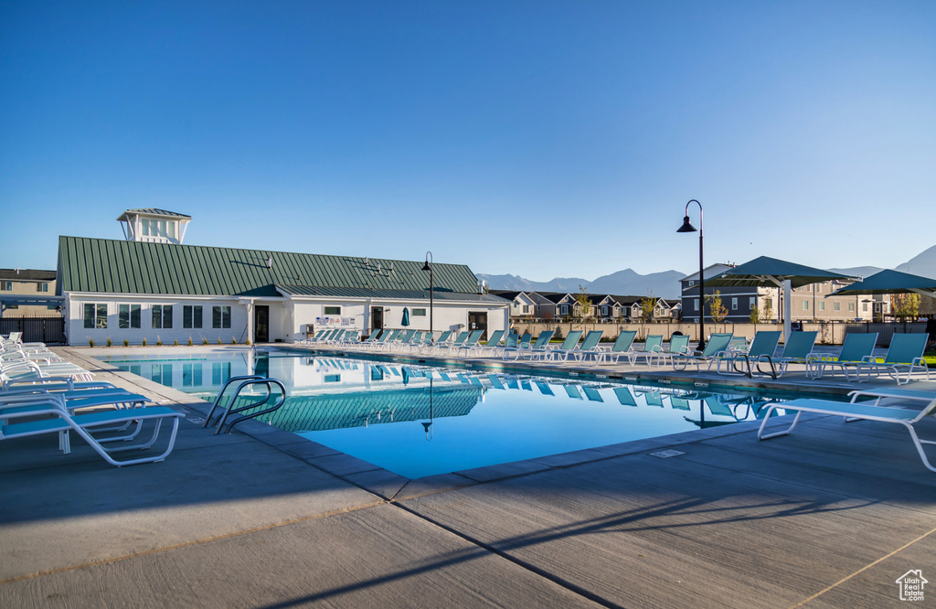 Community pool featuring a patio, a mountain view, fence, and a residential view