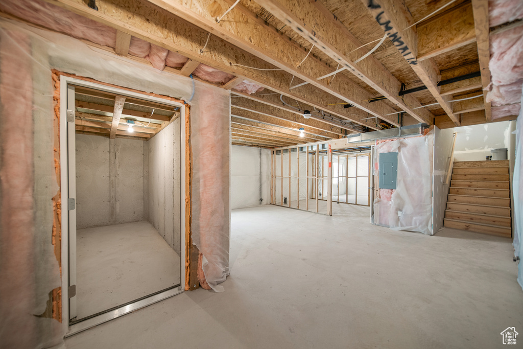 Unfinished basement featuring stairs and electric panel