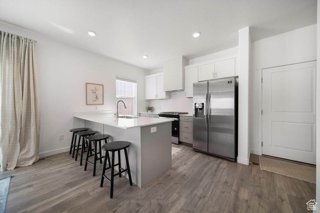Kitchen with a peninsula, wood finished floors, a breakfast bar, and stainless steel appliances