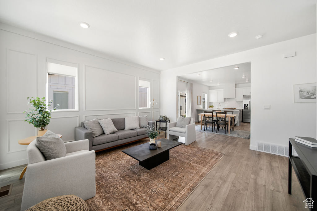 Living room with visible vents, recessed lighting, a decorative wall, and light wood-type flooring