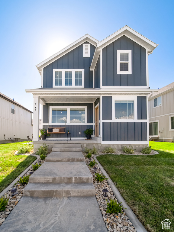 View of front of home with a front lawn, board and batten siding, and covered porch