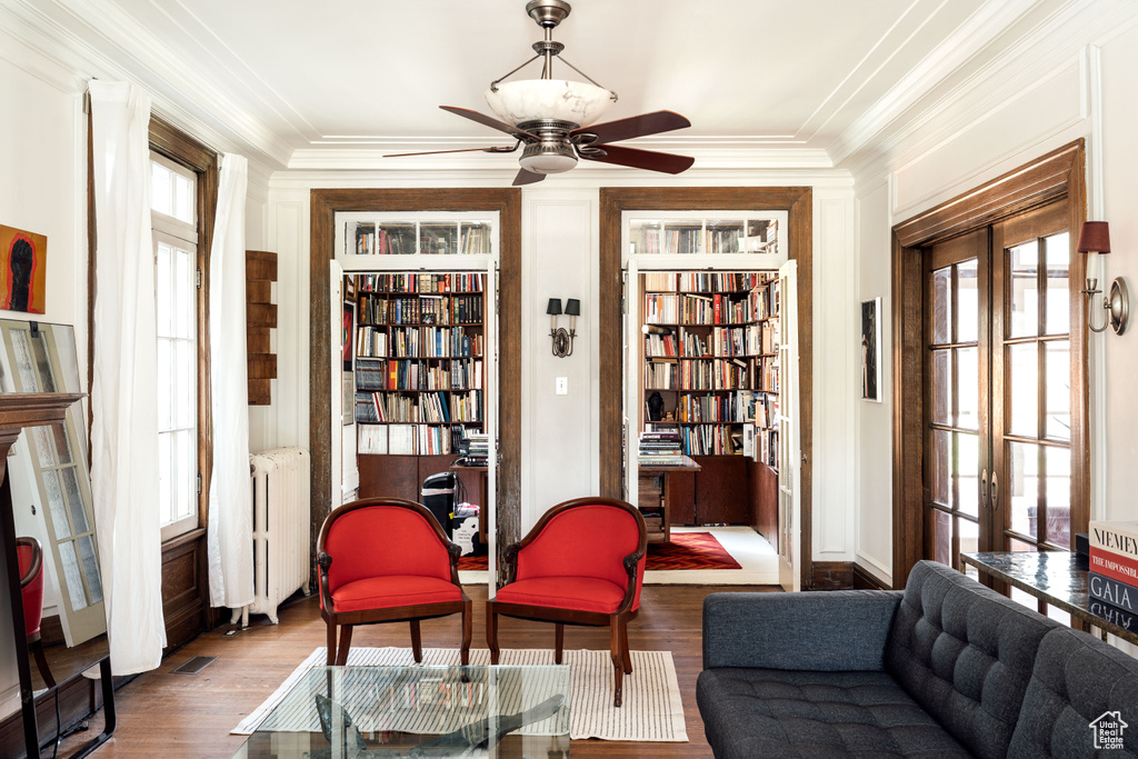 Sitting room with radiator heating unit, ceiling fan, ornamental molding, wood finished floors, and built in features
