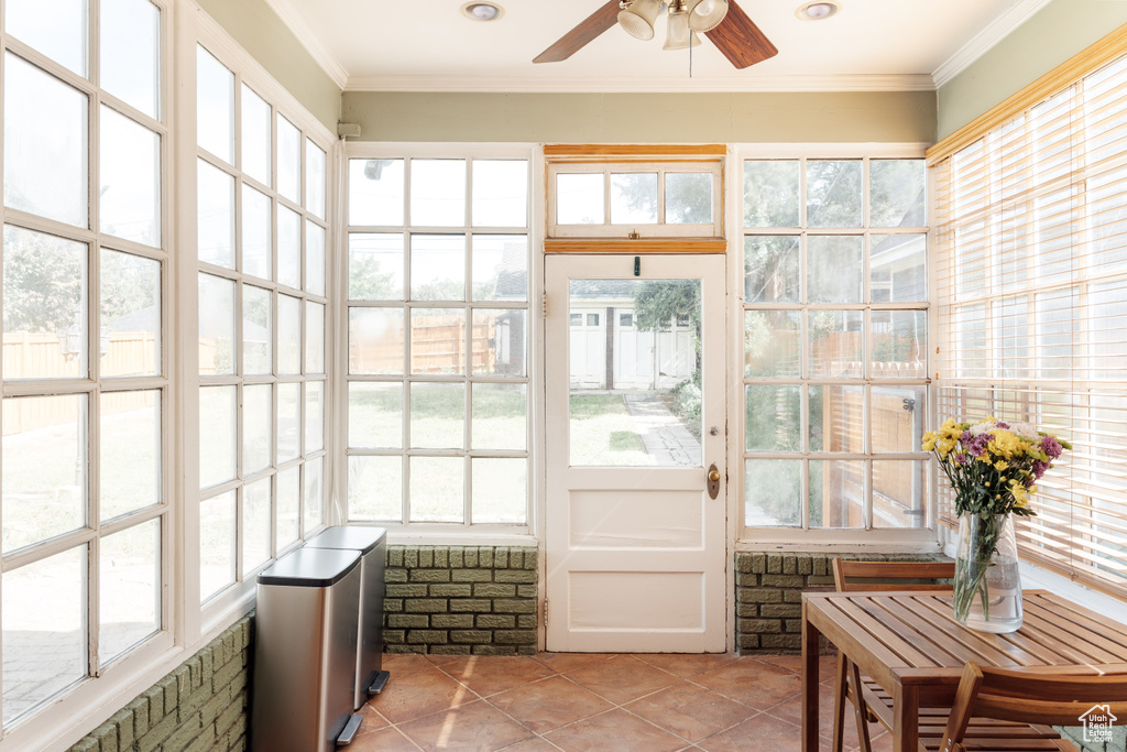 Sunroom with tile patterned floors, ceiling fan, ornamental molding, and plenty of natural light