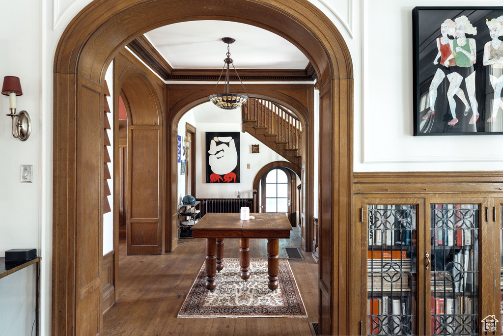 Foyer entrance with arched walkways, wood finished floors, ornamental molding, and a chandelier