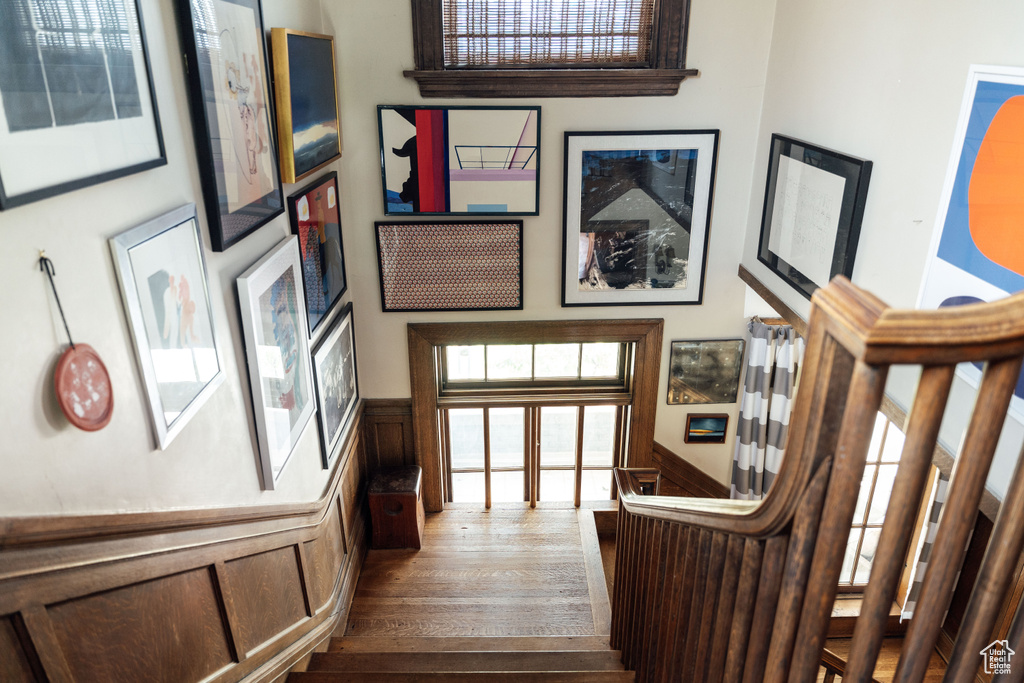 Staircase with wood finished floors and wainscoting