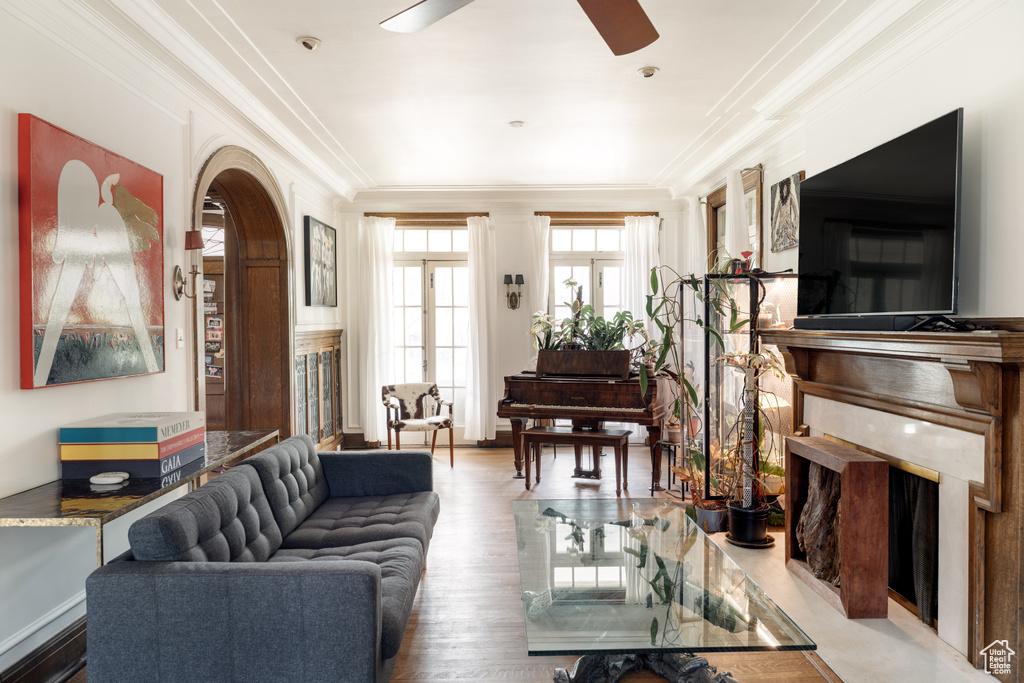 Living area with ornamental molding, ceiling fan, arched walkways, and wood finished floors