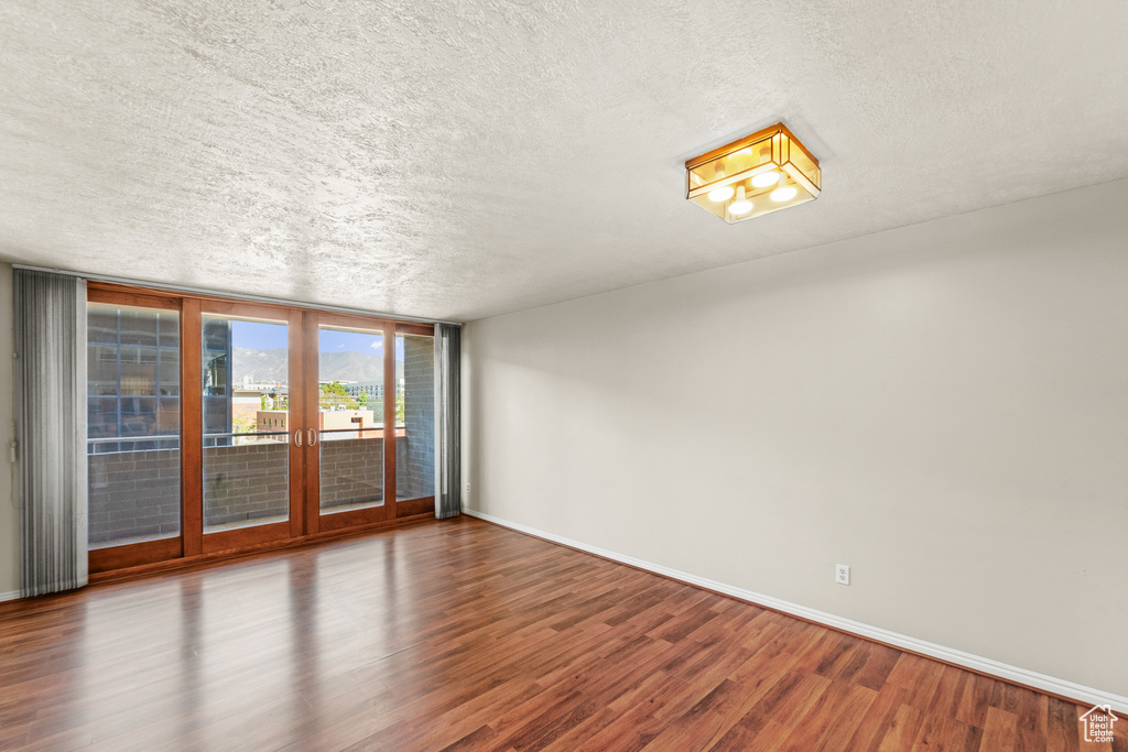 Unfurnished room with a textured ceiling, baseboards, and wood finished floors