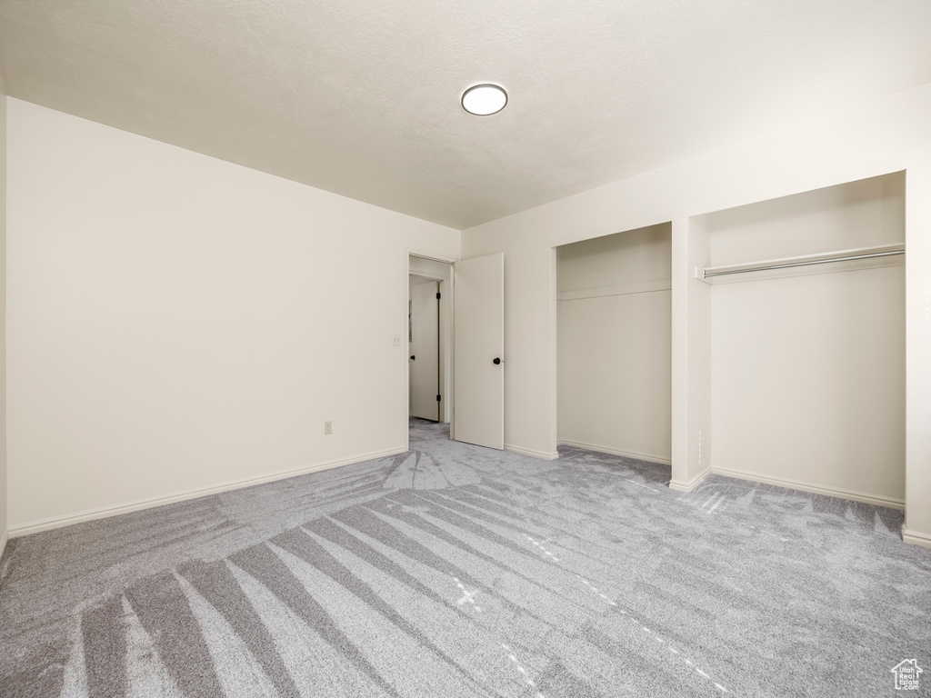 Unfurnished bedroom featuring carpet floors, multiple closets, and baseboards