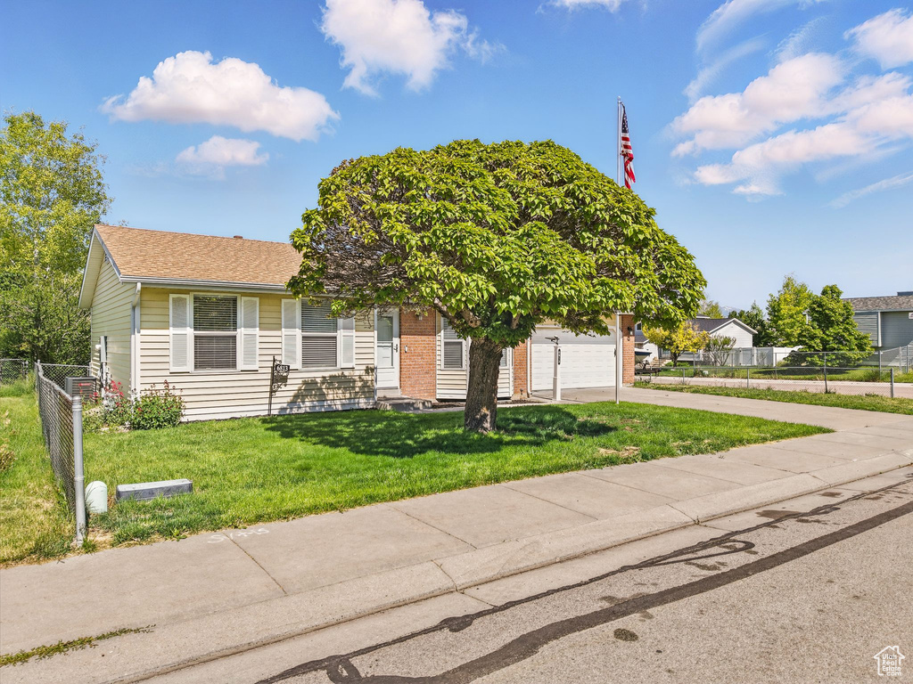 View of property hidden behind natural elements with concrete driveway, brick siding, and roof with shingles