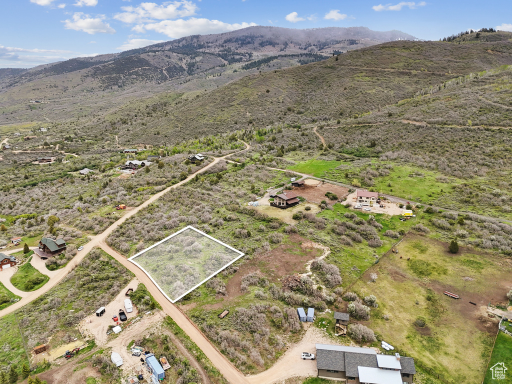 Aerial overview of property's location with property parcel outlined, a mountain backdrop, and rural landscape