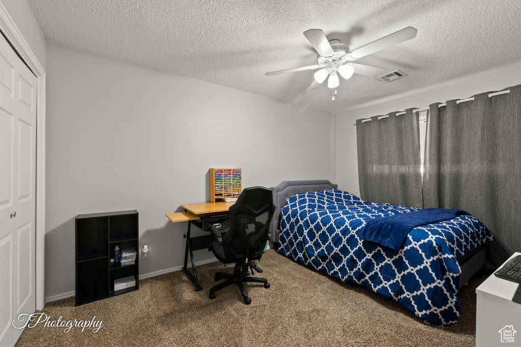 Carpeted bedroom featuring a closet, ceiling fan, a textured ceiling, and baseboards