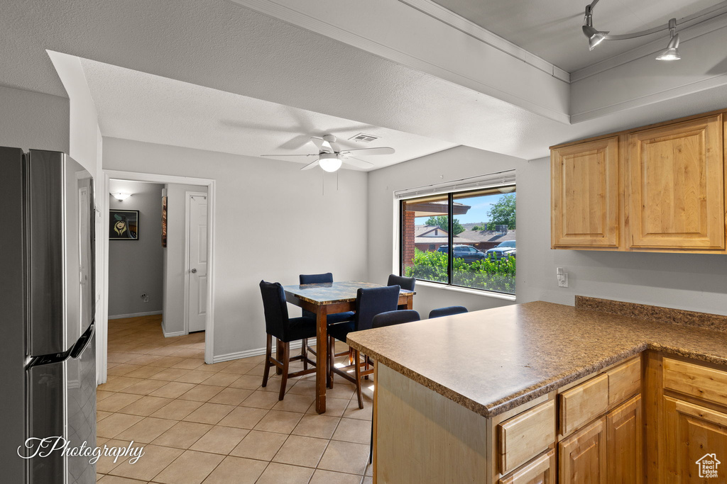 Kitchen featuring freestanding refrigerator, light tile patterned floors, ceiling fan, a peninsula, and track lighting