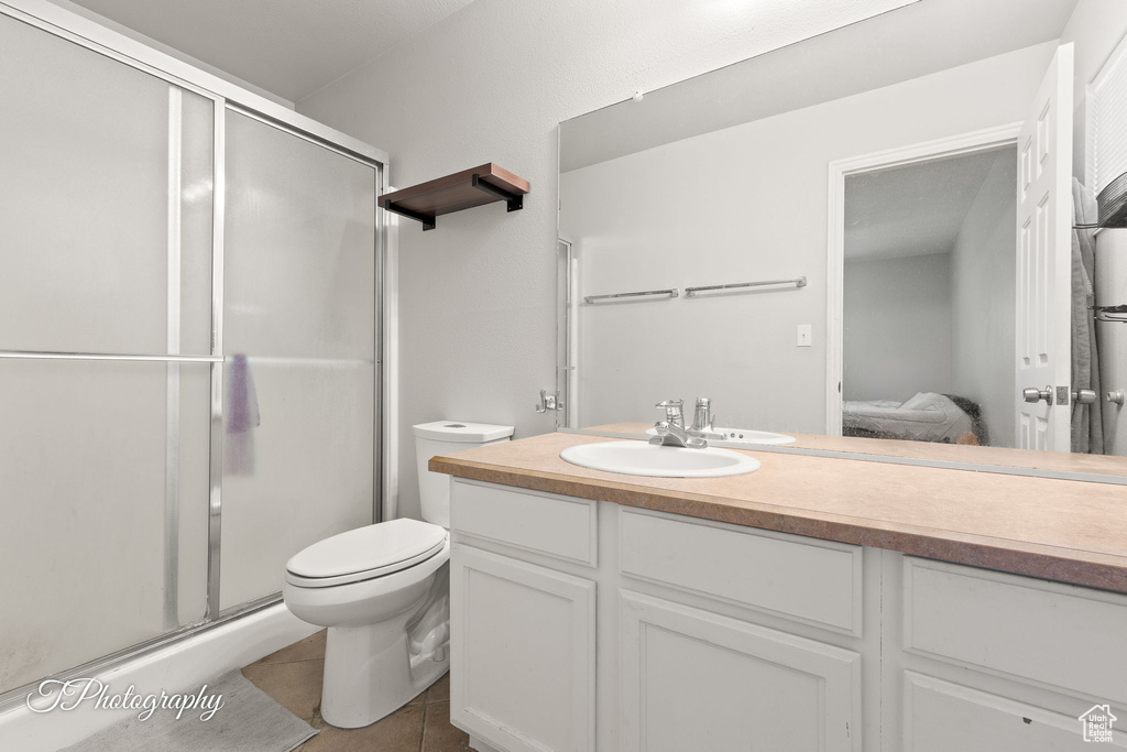 Ensuite bathroom featuring vanity, toilet, a shower stall, and tile patterned floors