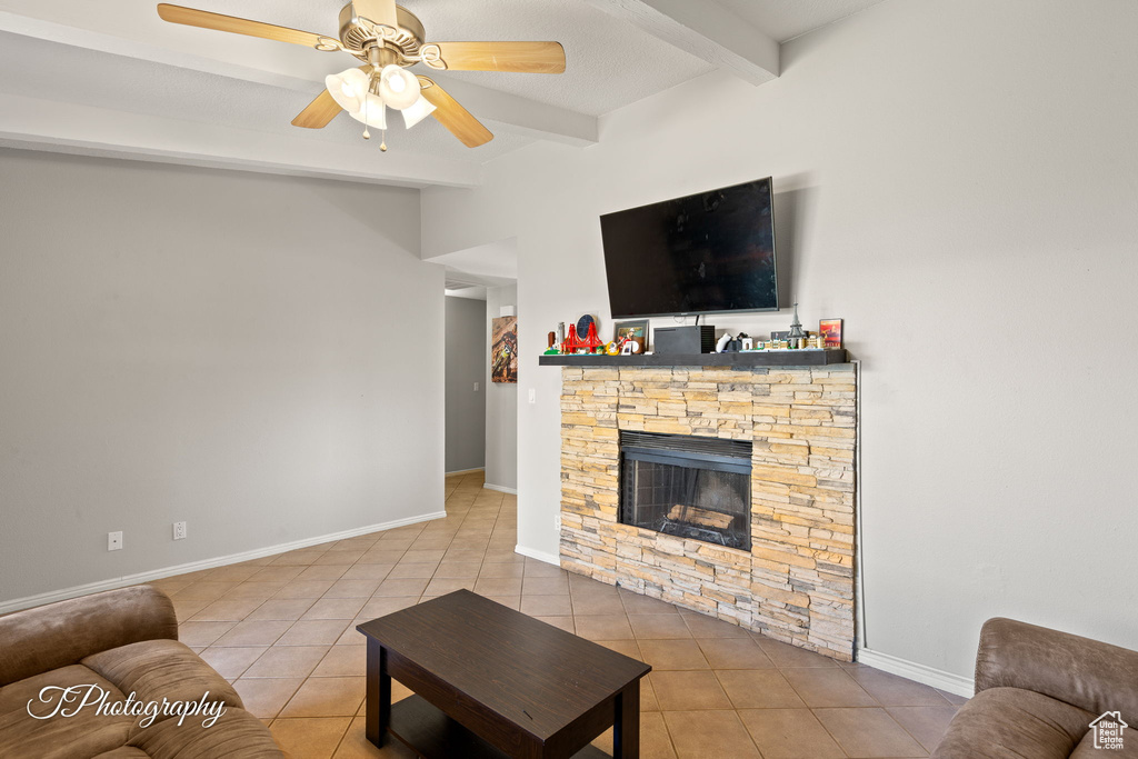Living area with beamed ceiling, tile patterned flooring, a fireplace, ceiling fan, and baseboards