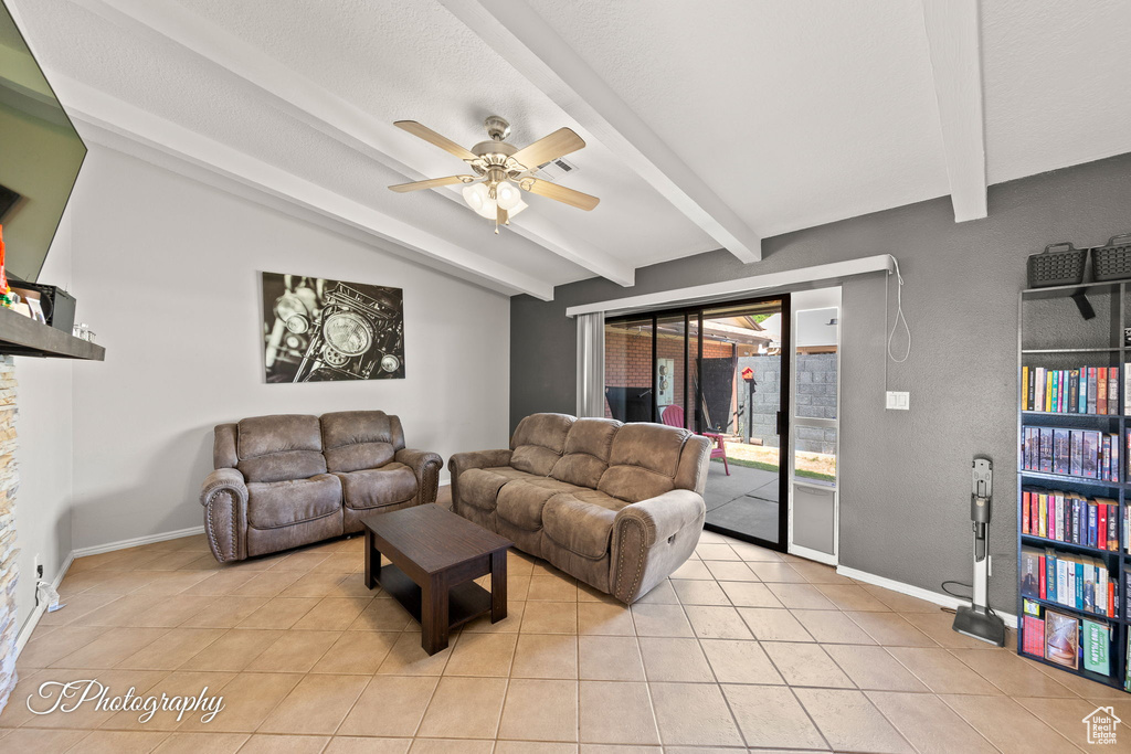 Living area featuring light tile patterned flooring, beam ceiling, ceiling fan, and baseboards