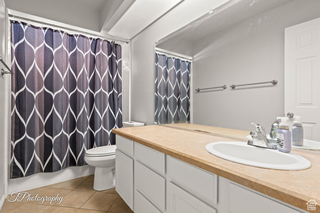 Bathroom with tile patterned floors, toilet, vanity, and shower / bath combo with shower curtain
