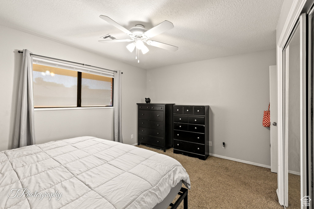 Carpeted bedroom with a textured ceiling and a ceiling fan