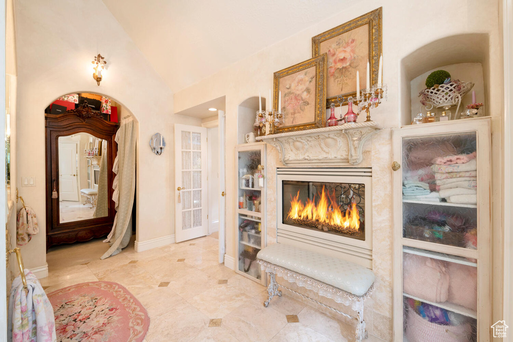 Interior space featuring lofted ceiling, baseboards, and a glass covered fireplace