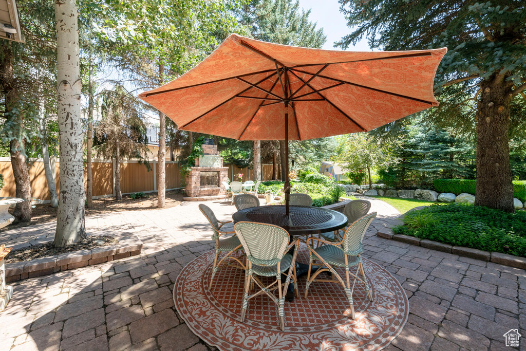 View of patio / terrace featuring fence, an outdoor stone fireplace, and outdoor dining area