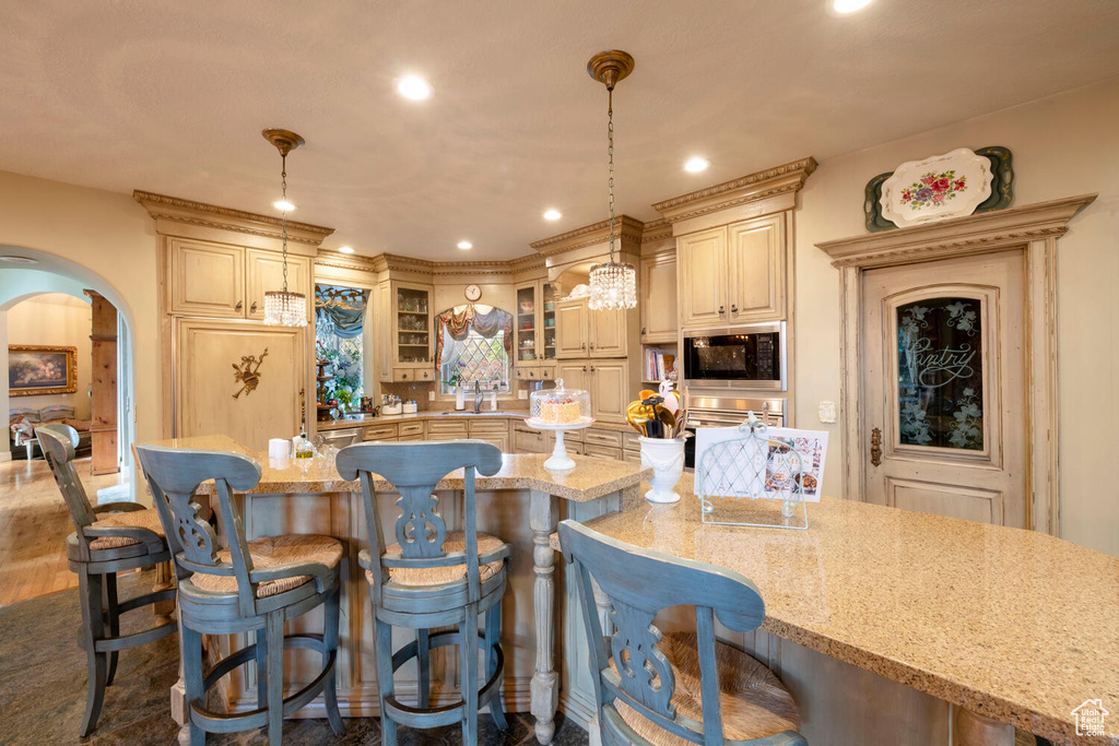 Kitchen with light stone counters, built in microwave, arched walkways, and a breakfast bar