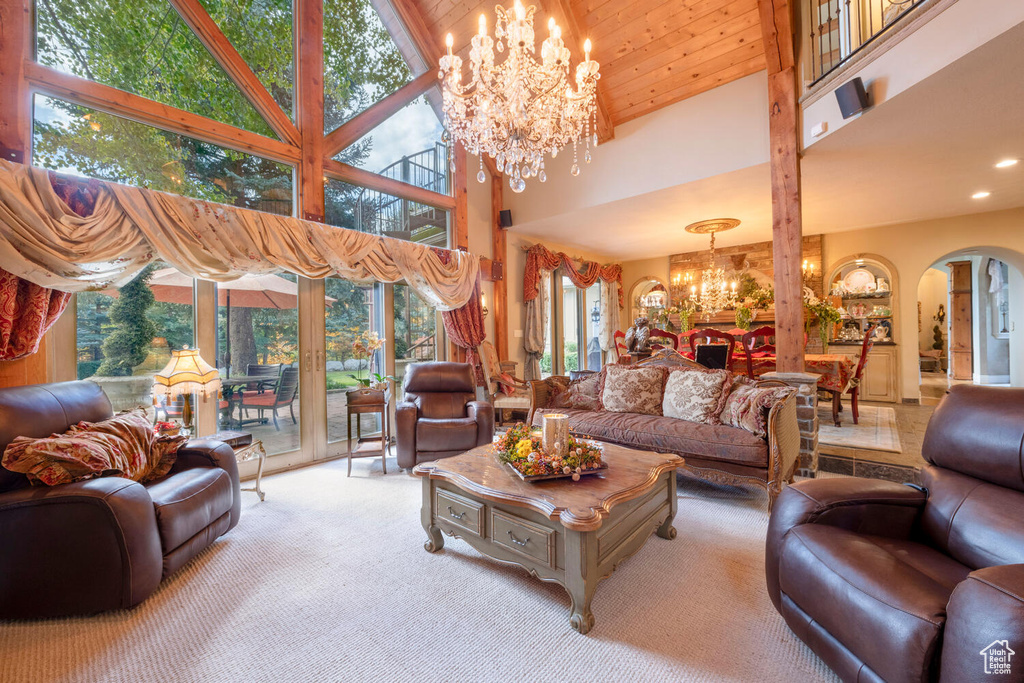 Carpeted living room featuring an inviting chandelier, a high ceiling, arched walkways, and recessed lighting