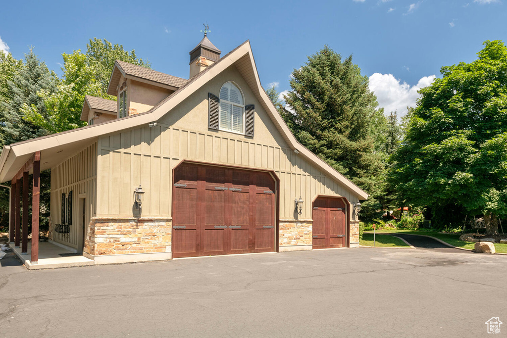 View of side of home featuring a garage, a barn, stone siding, an outbuilding, and board and batten siding