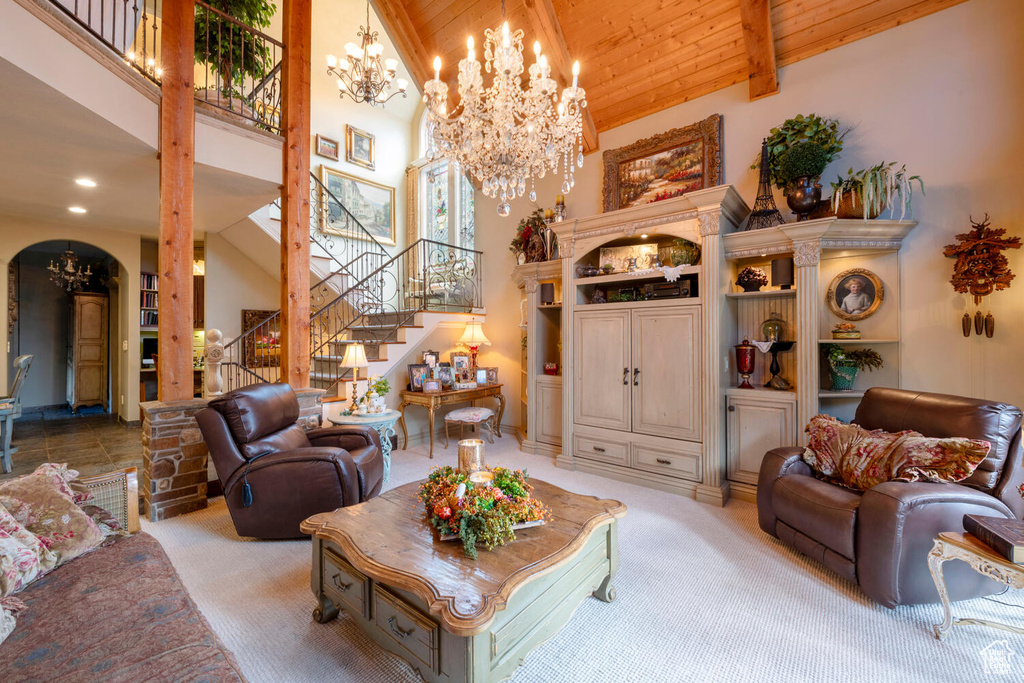 Carpeted living area with arched walkways, high vaulted ceiling, wooden ceiling, stairs, and an inviting chandelier