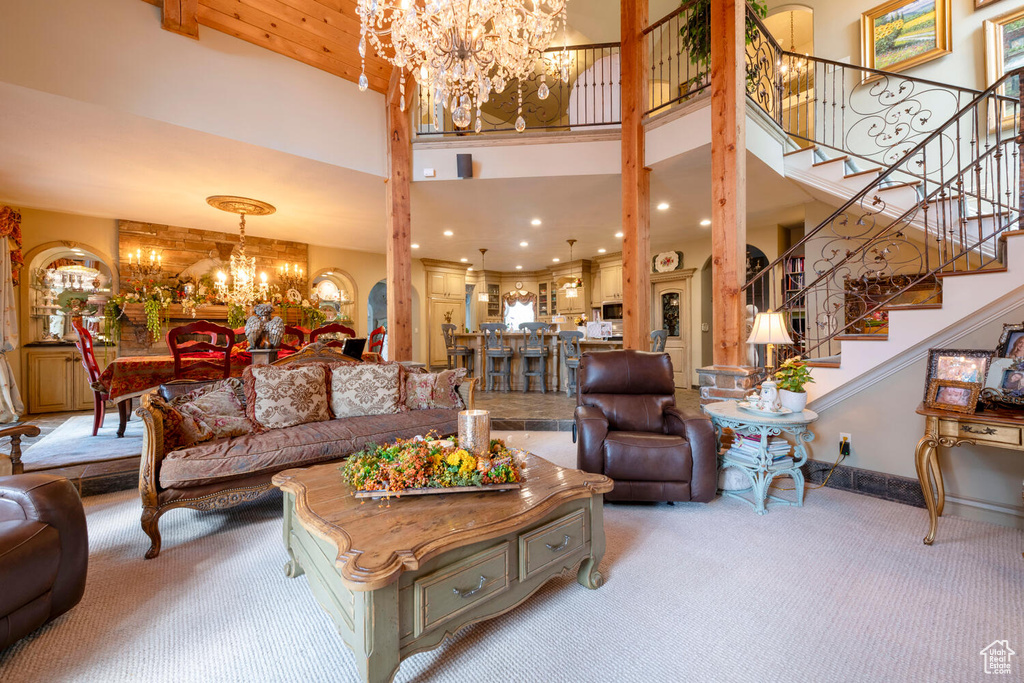 Living room with a high ceiling, stairs, a chandelier, and light colored carpet