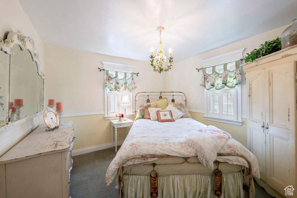 Carpeted bedroom featuring a chandelier and baseboards