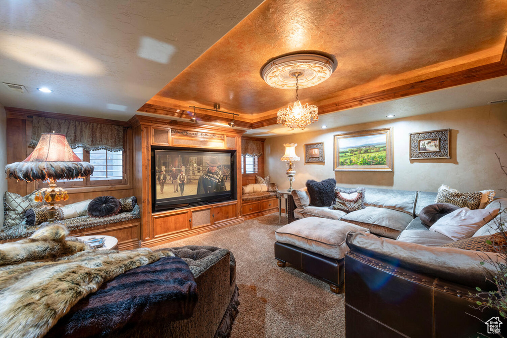 Carpeted living room with a raised ceiling, visible vents, and an inviting chandelier