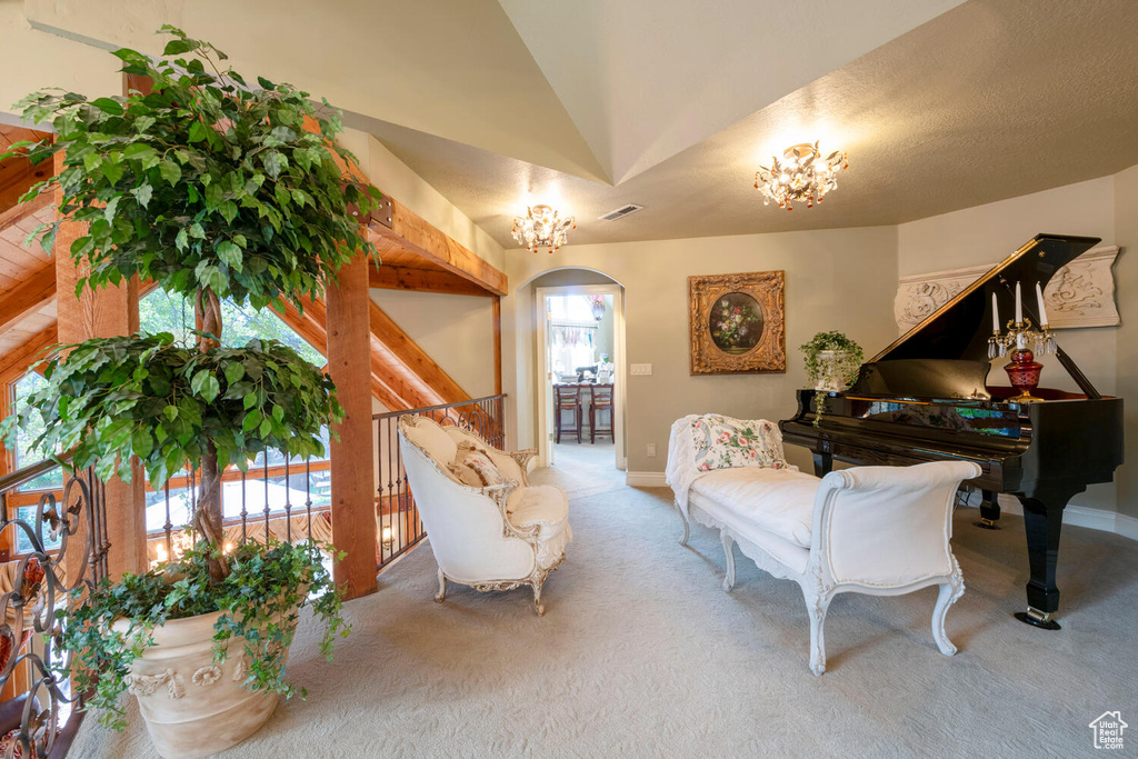 Living area featuring carpet floors, arched walkways, lofted ceiling, visible vents, and baseboards