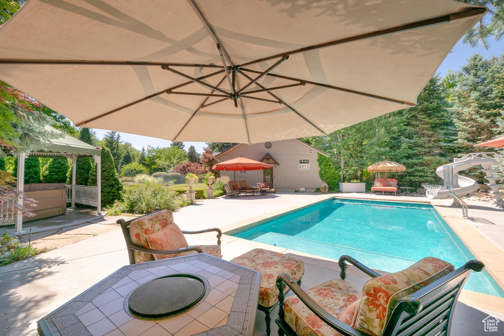 Pool with outdoor dining area, a patio area, a gazebo, and a water slide