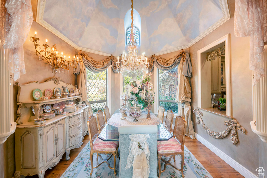 Dining space with lofted ceiling, a notable chandelier, baseboards, light wood-type flooring, and crown molding
