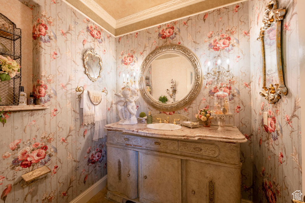 Bathroom featuring wallpapered walls, baseboards, and vanity