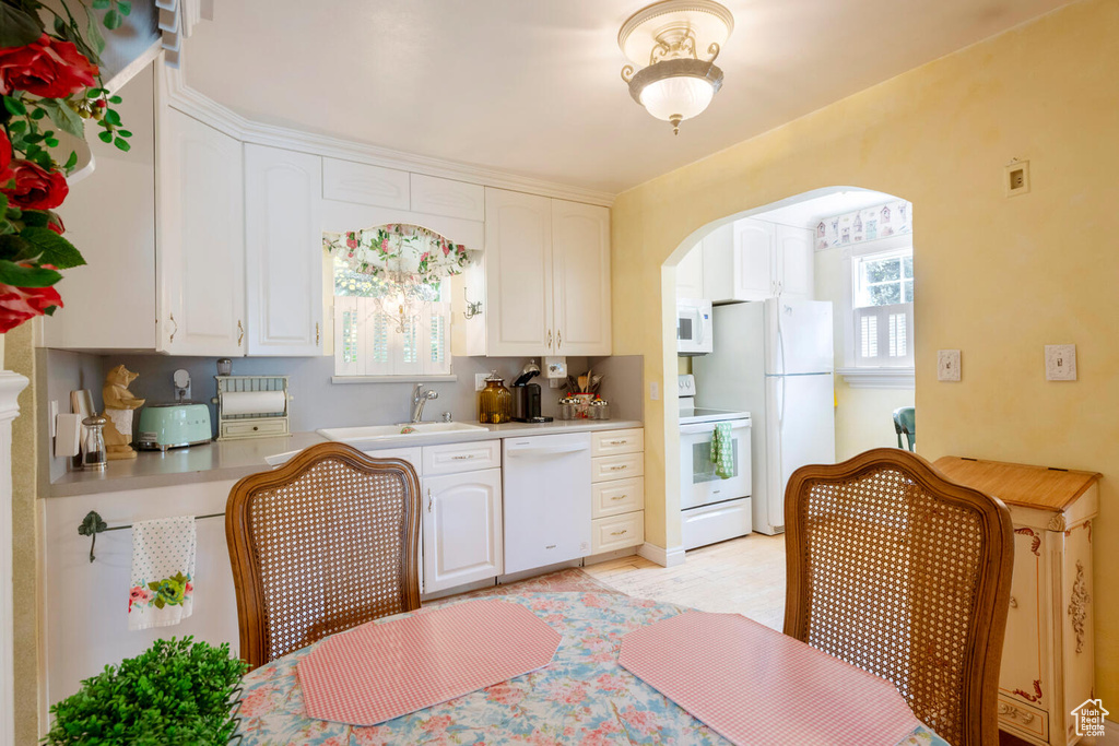 Kitchen with light countertops, white appliances, white cabinetry, and a sink