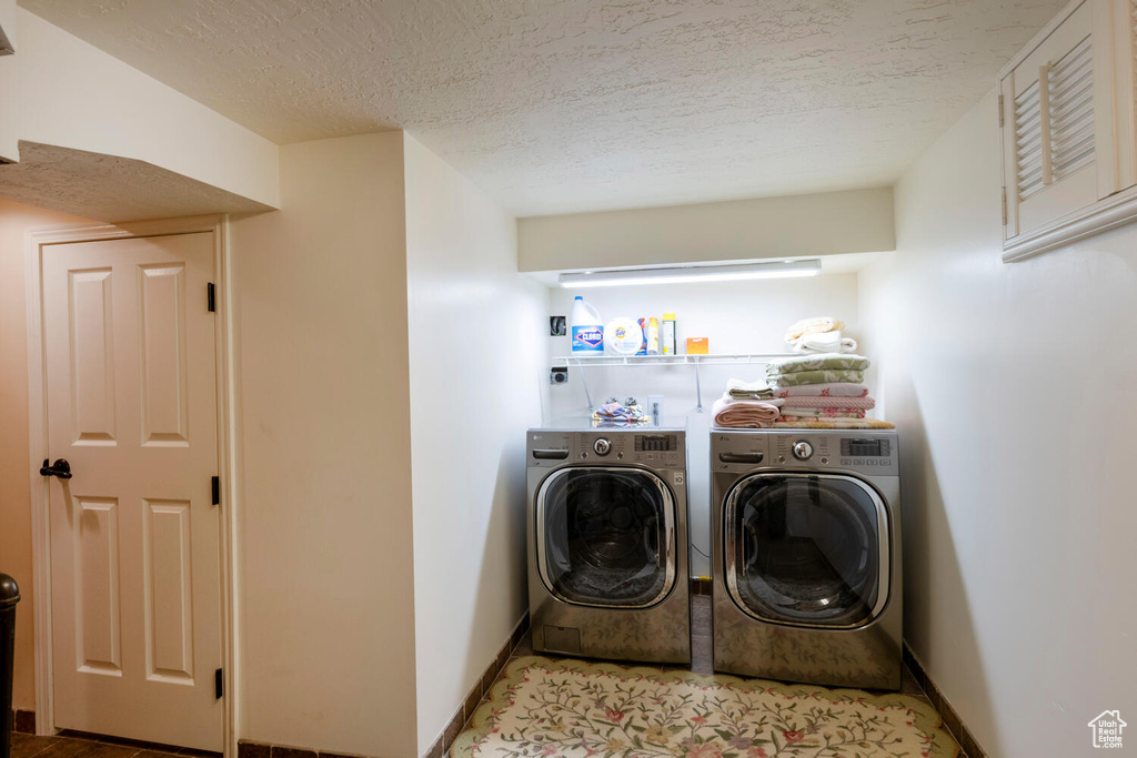 Laundry room featuring laundry area, baseboards, washer and clothes dryer, and a textured ceiling