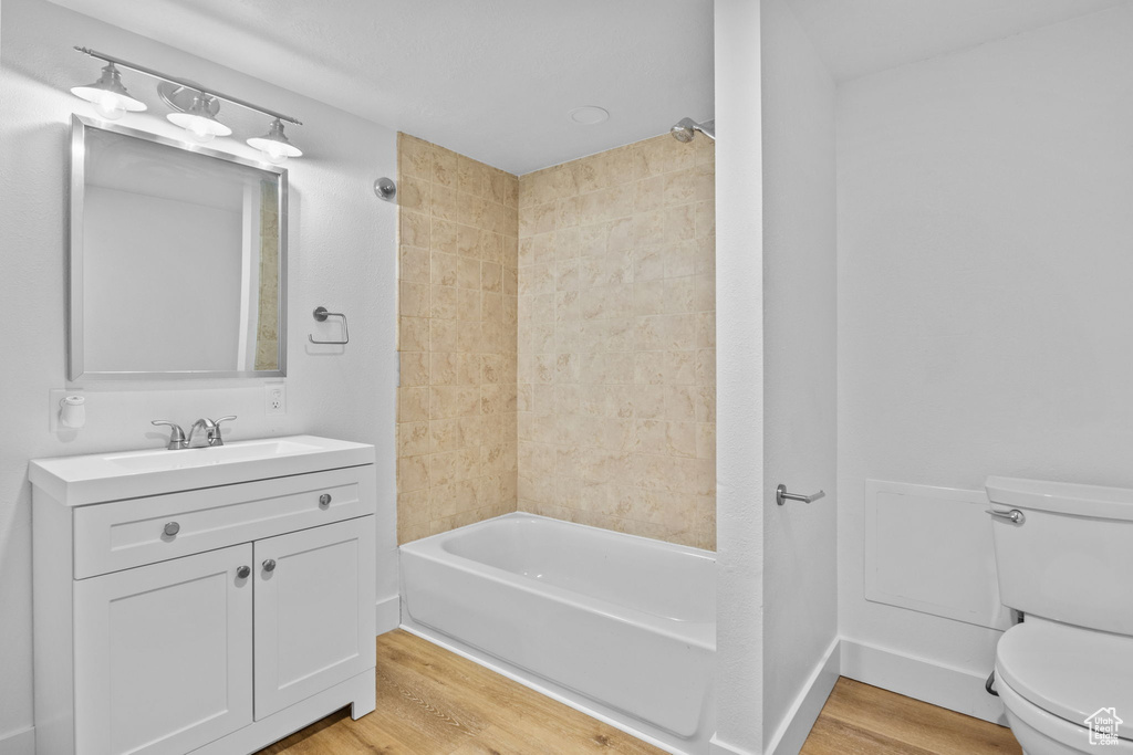 Bathroom with toilet, vanity, bathing tub / shower combination, and wood finished floors